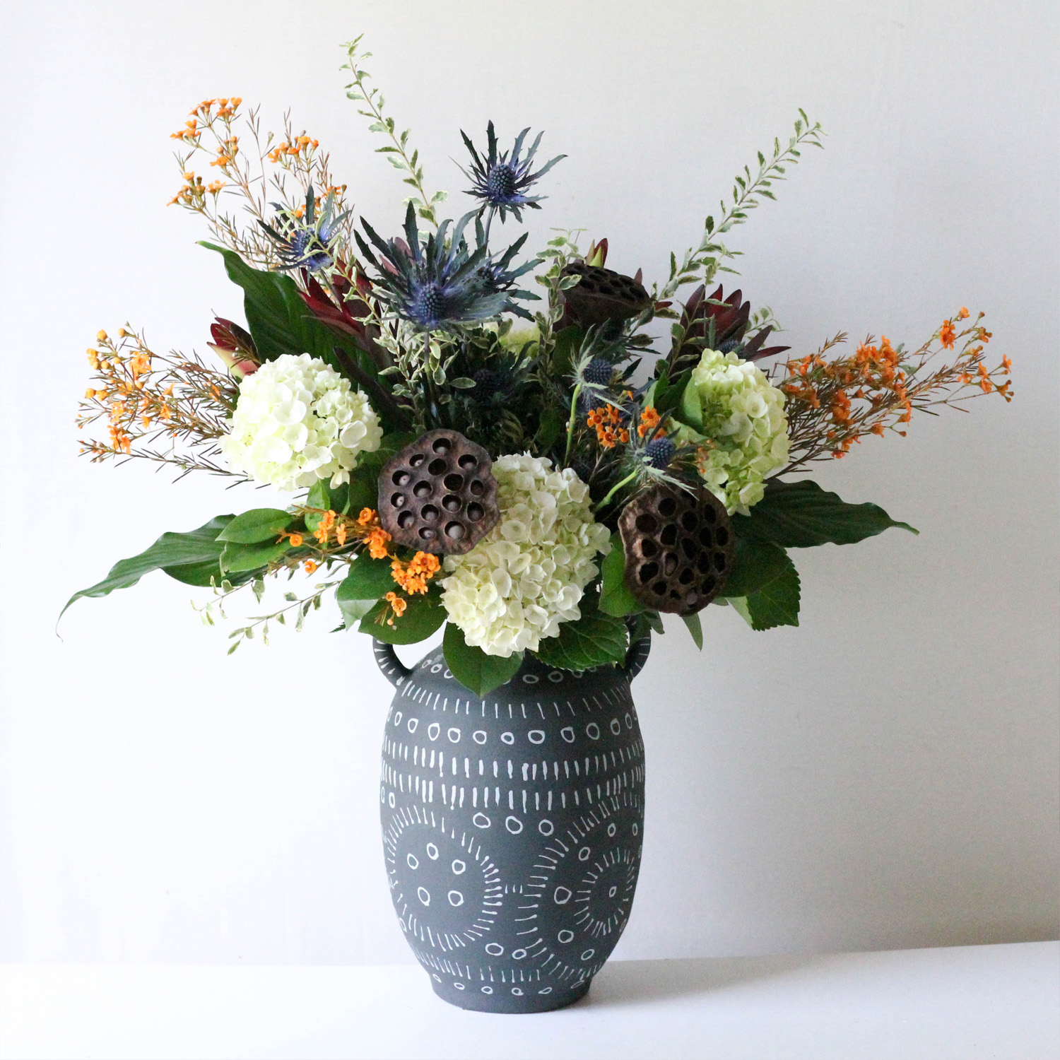 Valyrian - A visually captivating floral arrangement by combining contrasting textures of dried lotus pods with the softness of the mini green hydrangea
